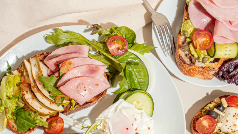Best sourdough bread with avocado, honey baked ham, caramelized onion, tomato salad, and capers.