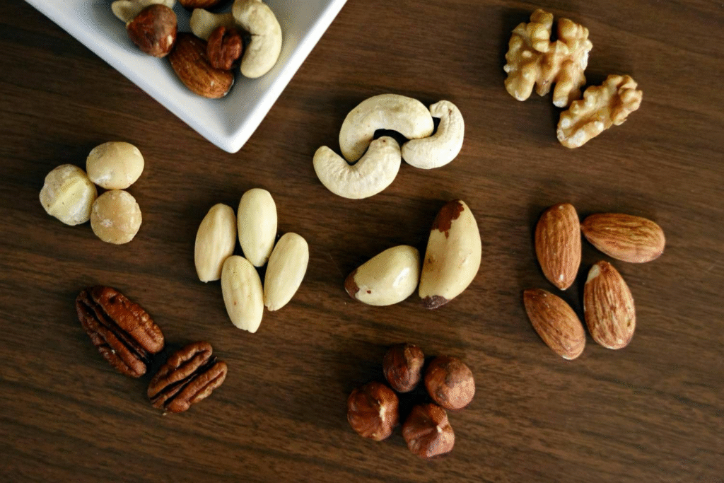 almonds, cashews, walnuts, and macadamias arranged neatly on a wooden table, showing healthy paleo foods.