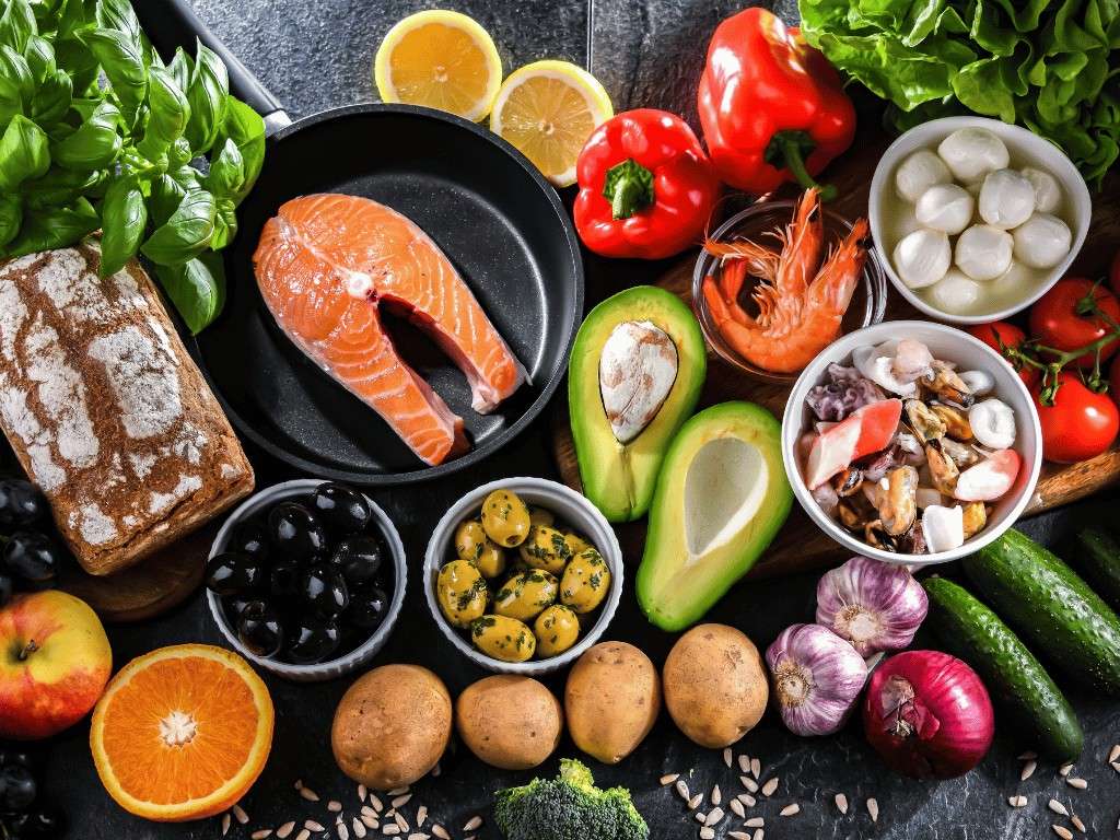 Healthy foods for PCOS diet including salmon, avocado, vegetables, fruits, and olive oil for hormone balance.