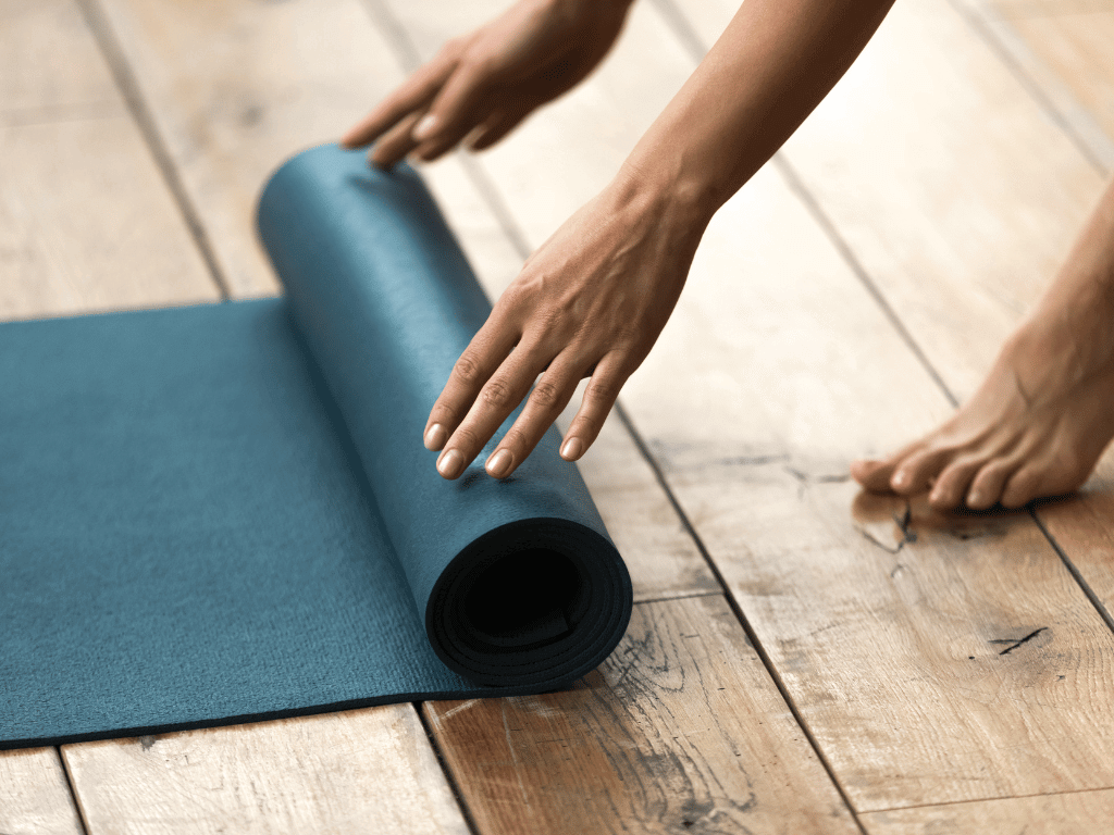 hands rolling up yoga mat representing best yoga mat of 2025