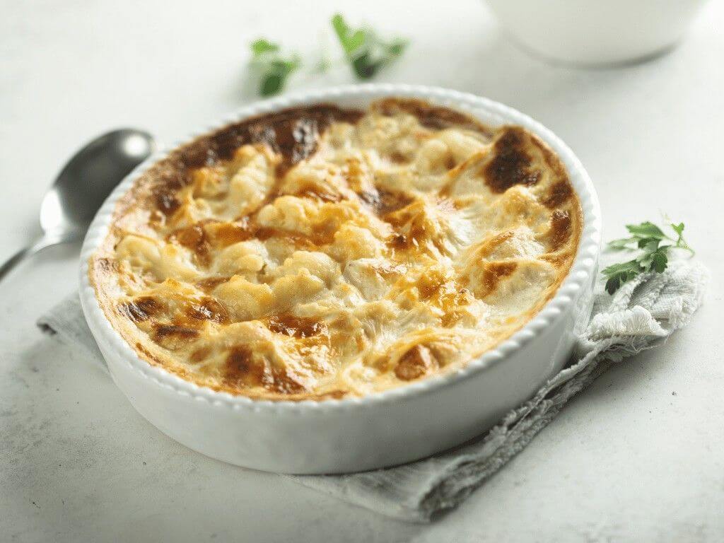Creamy baked cauliflower gratin served in a white dish, a delicious low carb pasta alternative for keto and gluten free diets.