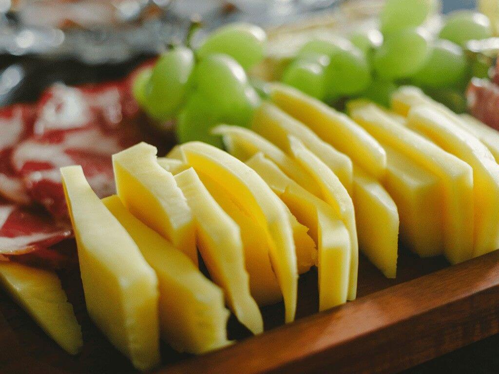 Sliced cheese sticks served with fresh green grapes, a quick gluten-free snack that’s creamy, salty, and sweet.