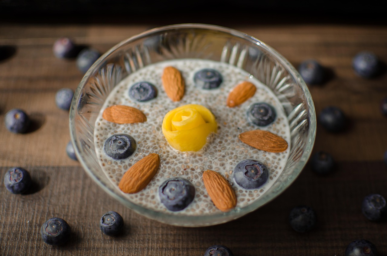 Glass of chia pudding topped with blueberries and raspberries, a creamy gluten-free snack rich in fiber and omega-3s.