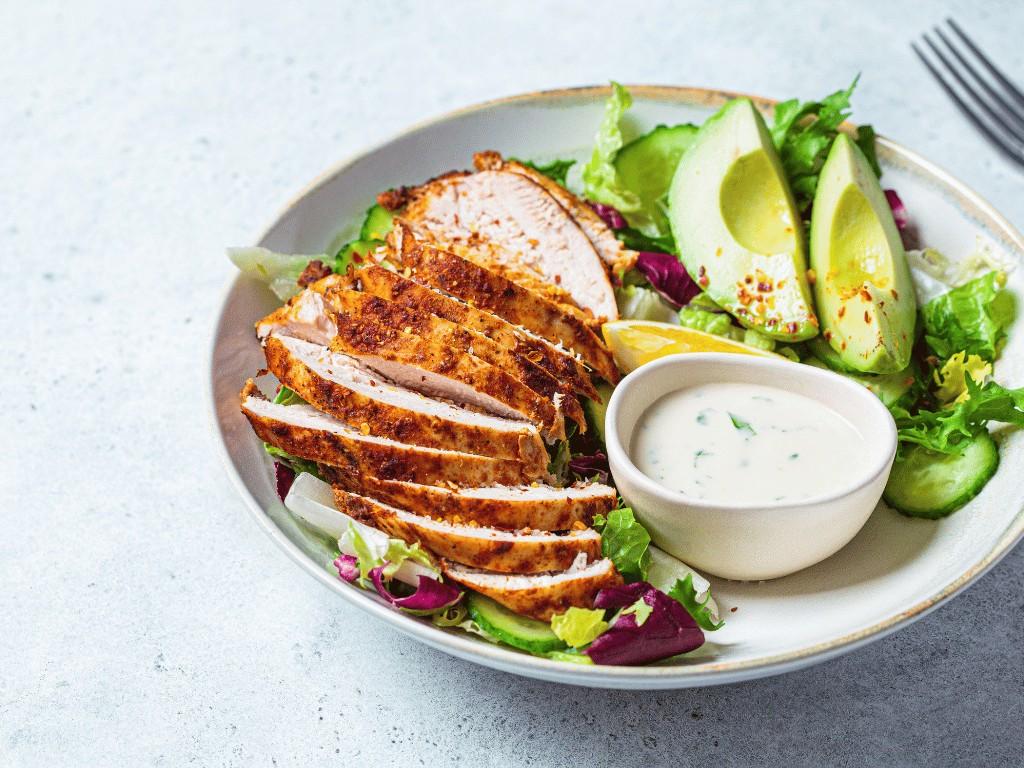 Grilled chicken salad with avocado and creamy dressing, a healthy meal prep recipe for balanced lunches or dinners.