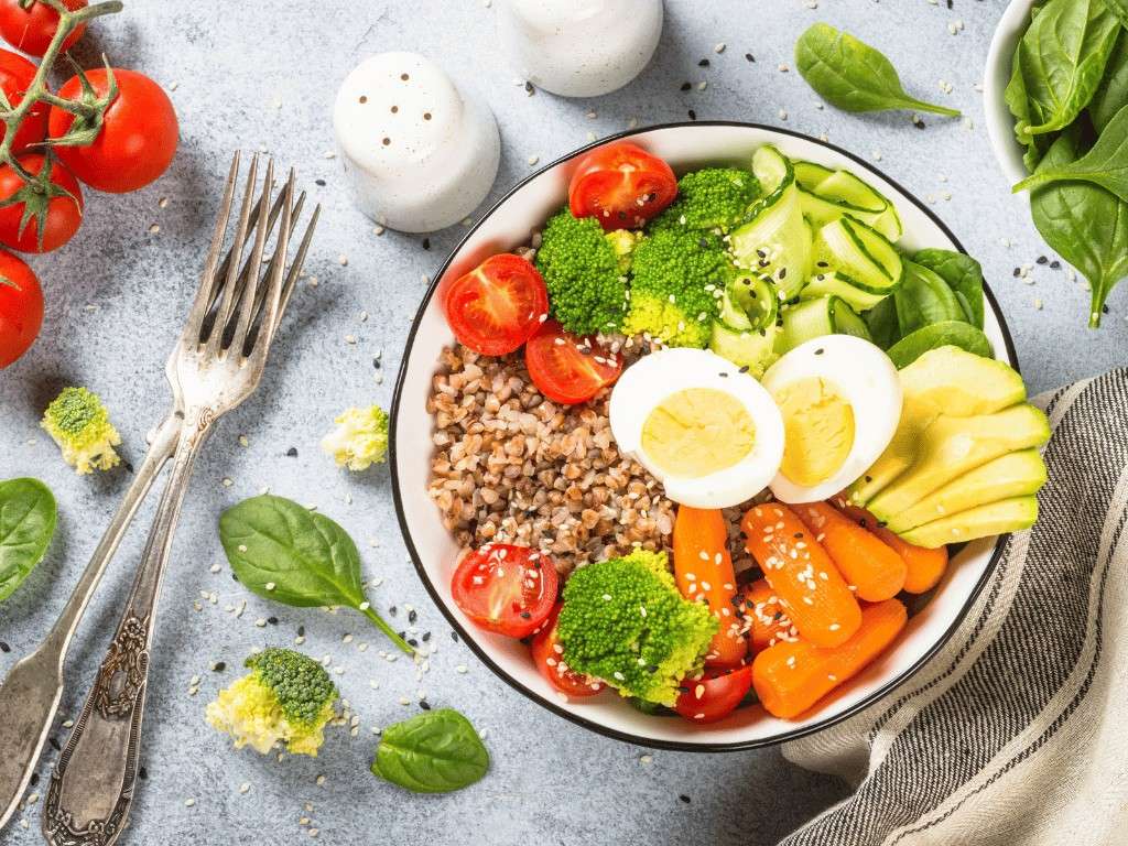 Healthy diet bowl with vegetables, avocado, eggs, and grains to support better body composition and lower fat mass.