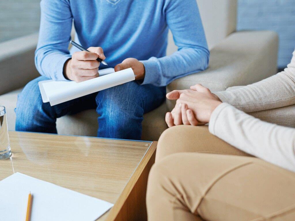 Therapist taking notes during psychotherapy session for eating disorder treatment.