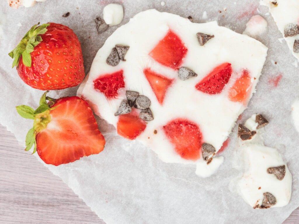 Frozen yogurt bark topped with strawberries and chocolate chips, a refreshing gluten-free dessert made with Greek yogurt.