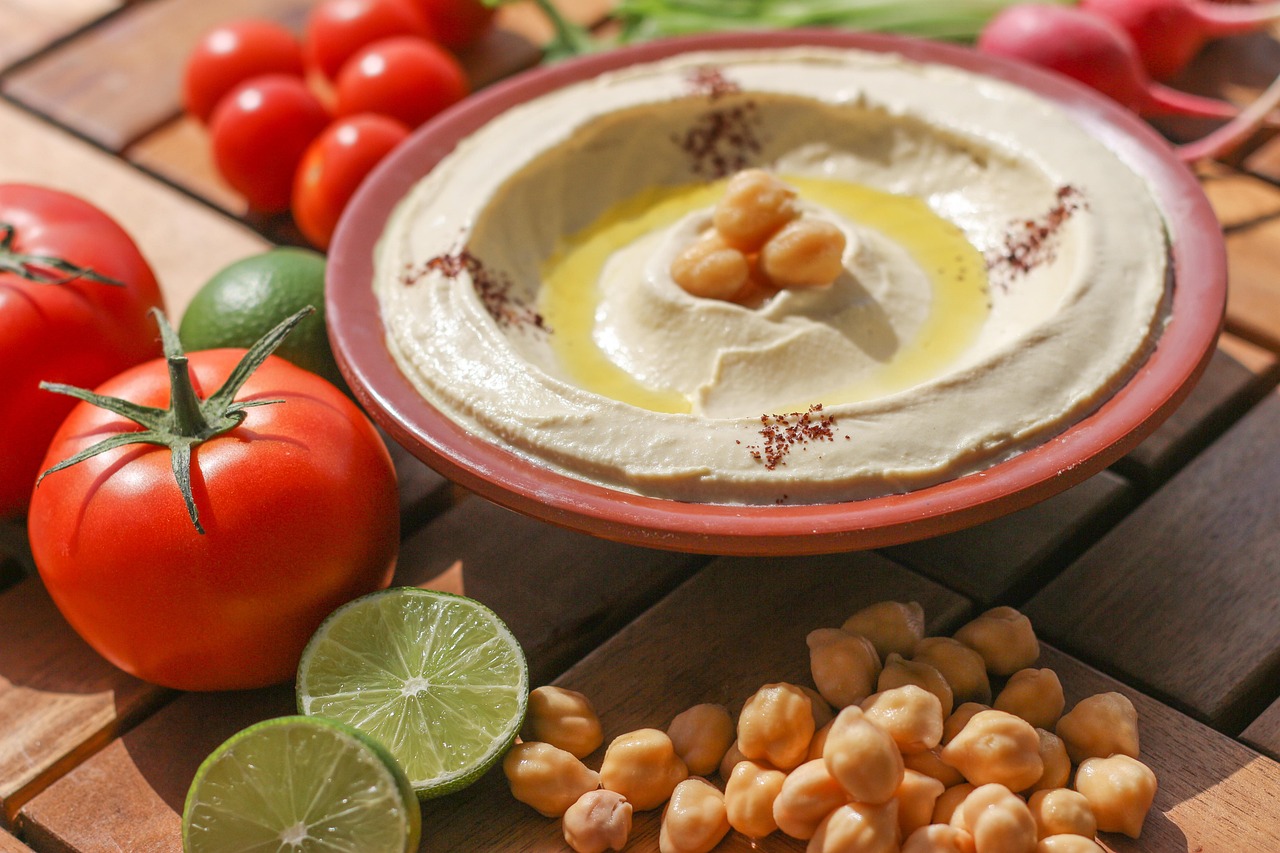 Creamy hummus made from chickpeas served with fresh tomatoes, limes, and chickpeas, a healthy gluten-free snack.