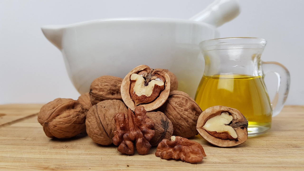 Walnuts and a glass jar of oil are healthy fat sources that support vitamin absorption and energy production.