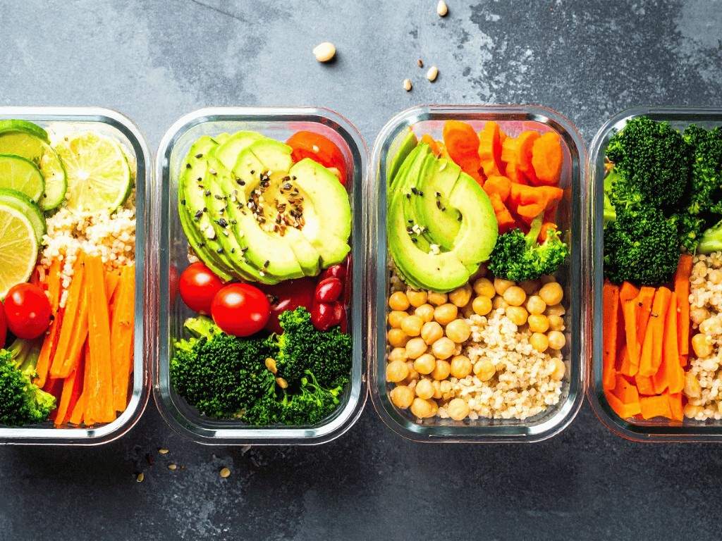 Glass containers with avocado, chickpeas, broccoli, and grains, showing how to meal prep nutritious lunches for a busy week.