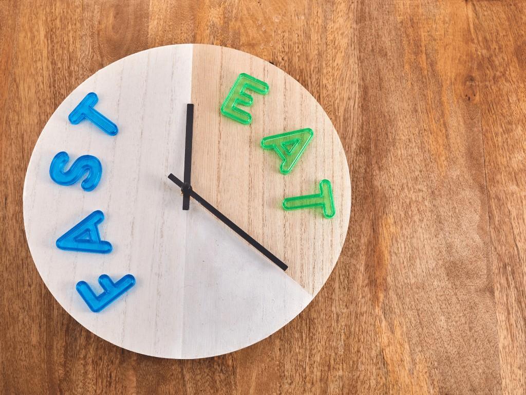 Clock labeled “fast” and “eat” represents intermittent fasting, a time restricted eating plan for weight loss and metabolic health.