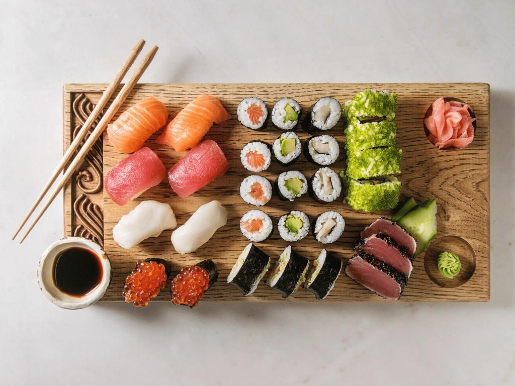 Assorted sushi rolls and sashimi served with soy sauce, wasabi, and pickled ginger, a balanced sushi meal featuring omega 3 fatty acids and lean protein.