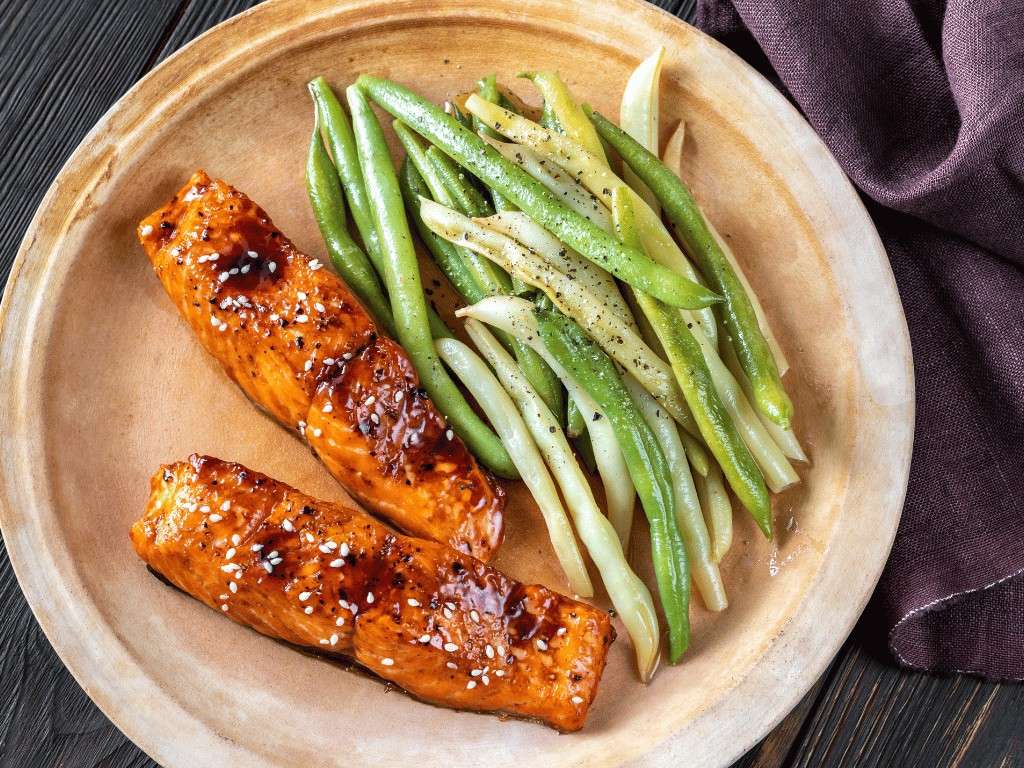 Low FODMAP baked salmon fillet with roasted pumpkin cubes and green beans on a plate.