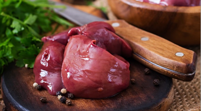 Fresh raw organ meats displayed on a chopping board, nutrient dense foods valued in the paleo food list diet for their health benefits.