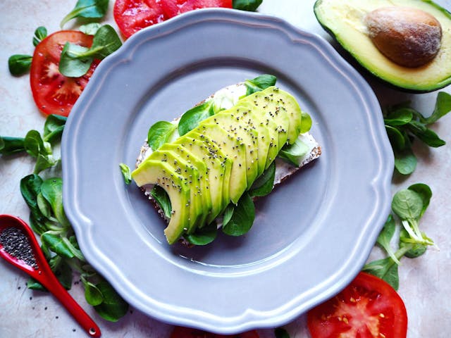 Creamy mashed avocado spread on gluten-free toast, topped with herbs, a healthy and filling breakfast choice.
