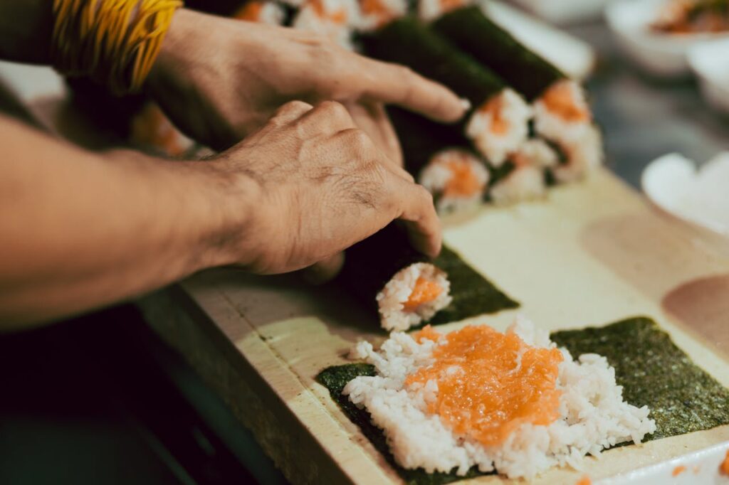 Chef preparing sushi roll with rice and seaweed on a bamboo mat, showing is sushi healthy ingredients like fish, rice, and balanced seasonings.