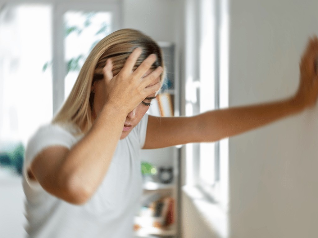 Woman feeling dizzy and holding her head, a possible side effect of prolonged dry fasting or low fluid intake.