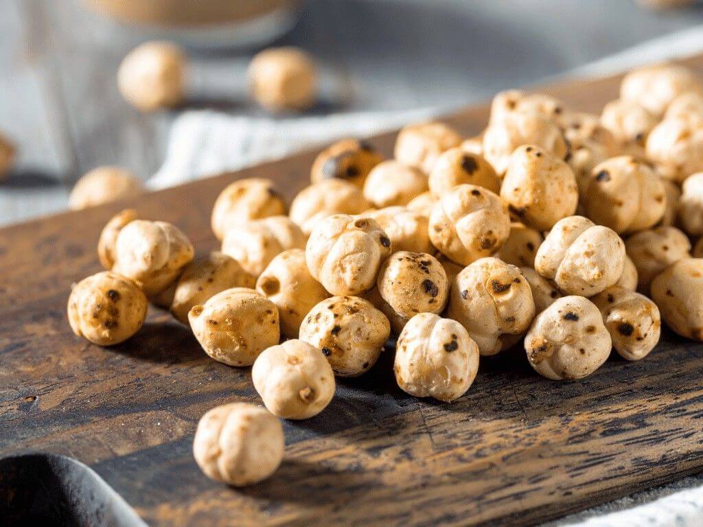 Crispy roasted chickpeas on a wooden board, a protein-rich gluten-free snack seasoned lightly with olive oil and spices.