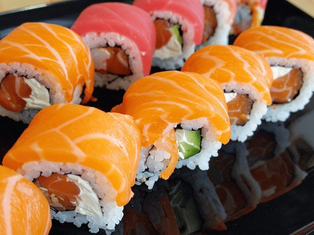 Colorful sushi rolls topped with salmon and tuna, featuring avocado and rice, highlighting is sushi healthy benefits with omega 3 fatty acids and lean protein.