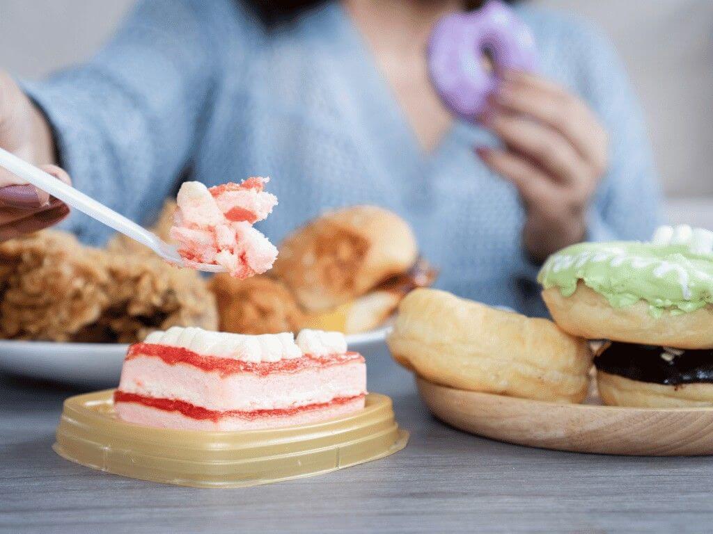 woman stress eating and indulging in fatty, sugary foods