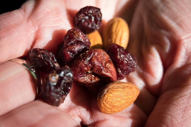 Handful of trail mix with almonds and dried cranberries, a quick gluten-free snack packed with fiber and healthy fats.