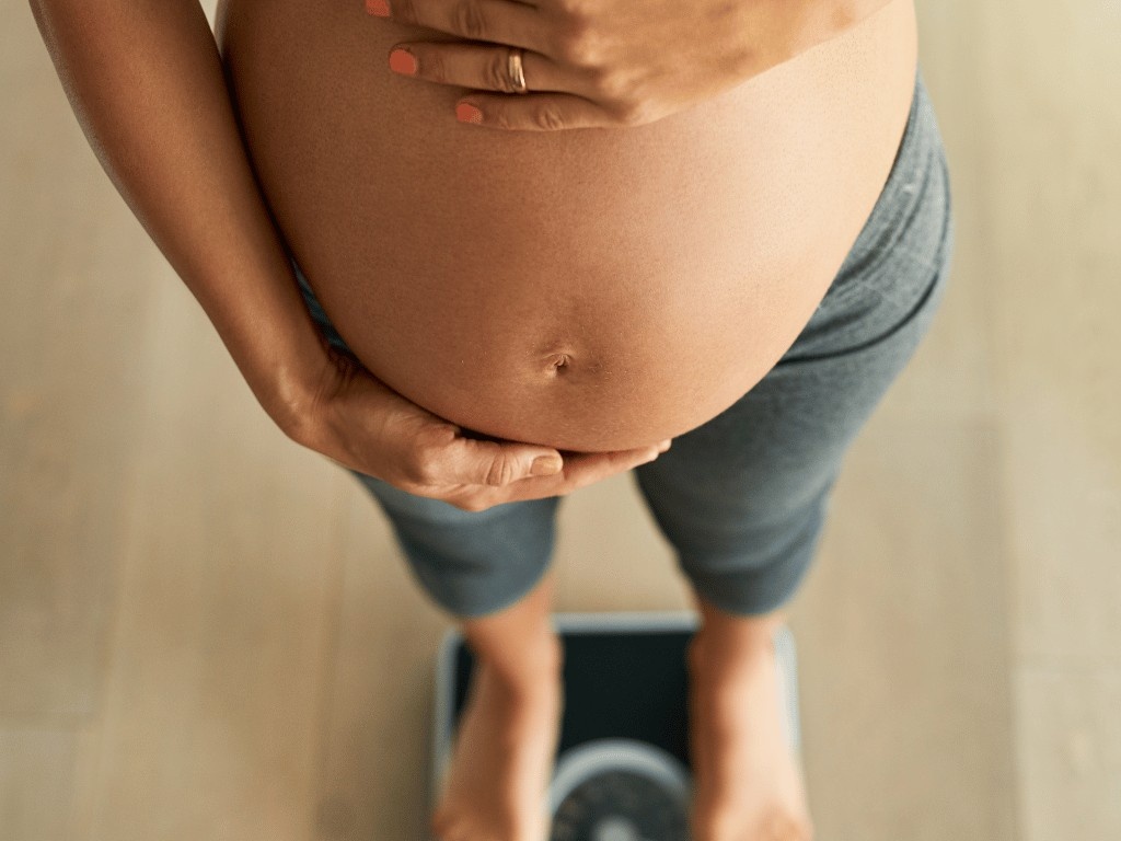 Pregnant woman standing on scale and healthy weight gain during pregnancy.