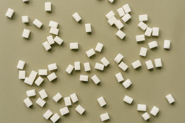 Sugar cube pieces scattered on a flat surface as artificial sweeteners used in Coke Zero and their role in health concerns.