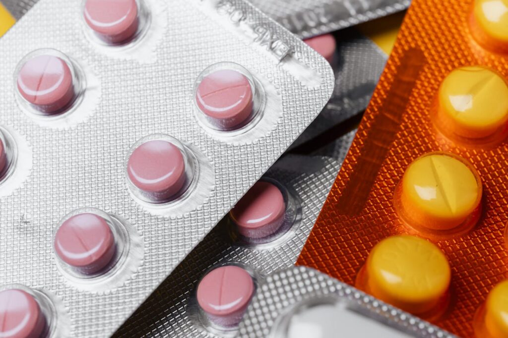 Blister packs of assorted tablets in silver and orange packaging arranged closely together to help relieve bloating.