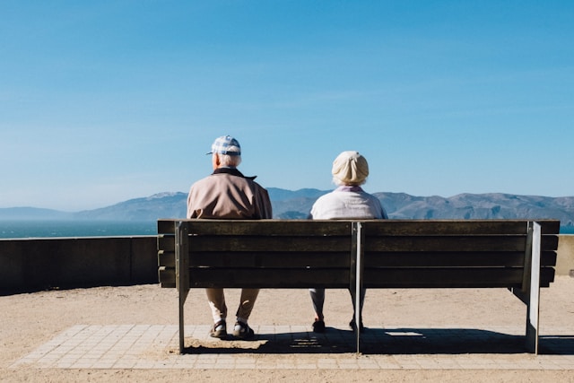 Elderly couple sitting on a bench outdoors, older age as a risk factor for SIBO