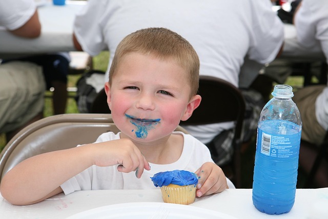 Child eating a blue frosted snack beside a sugary drink to show how sugar substitutes like those in Coke Zero may influence appetite and weight gain.