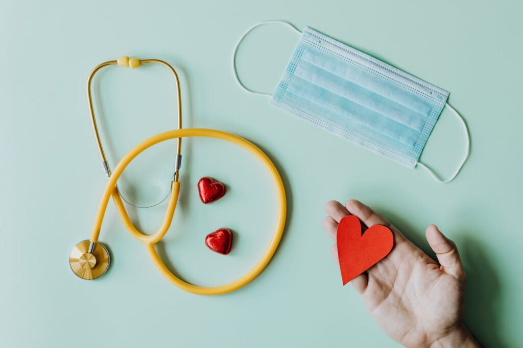 Stethoscope, surgical mask, and two small red heart shapes and a larger red heart, when to seek medical attention for bloating.