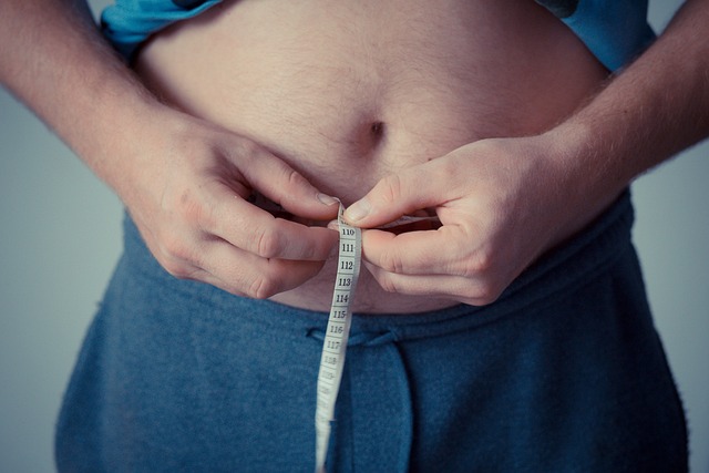 Person measuring their waist. Drinking diet soda is linked to increased waist size over time.
