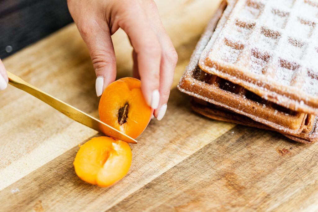 Fresh apricot being sliced on a wooden board