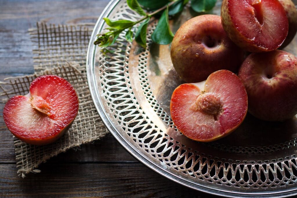 Fresh plums and halved red plum on a plate