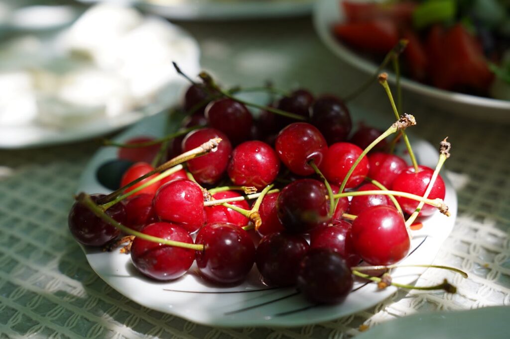 Fresh red cherries on a white plate with stems attached