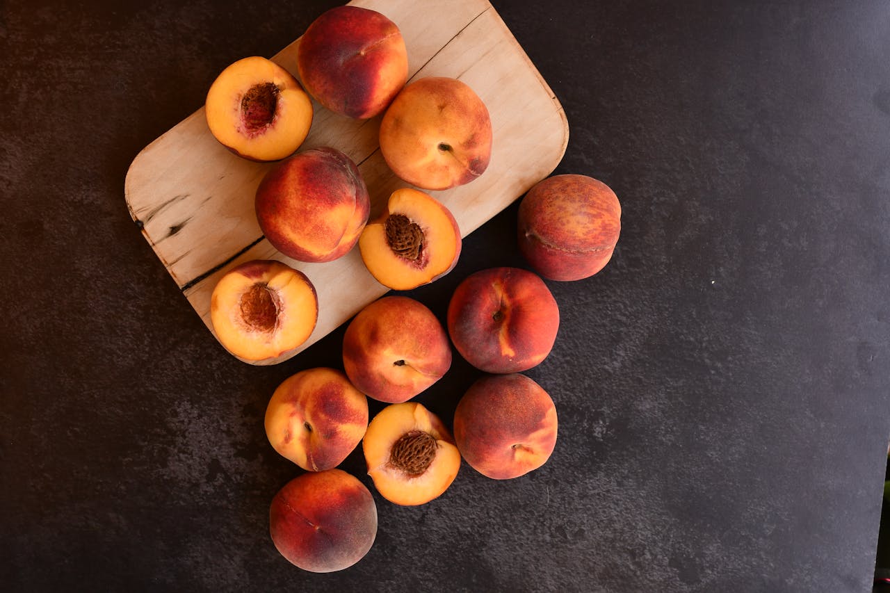 Fresh stone fruit like peaches and nectarines on a wooden board showing colorful drupes rich in nutrients