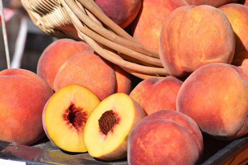 Basket of ripe peaches and halved peach showing stone fruit flesh and pit