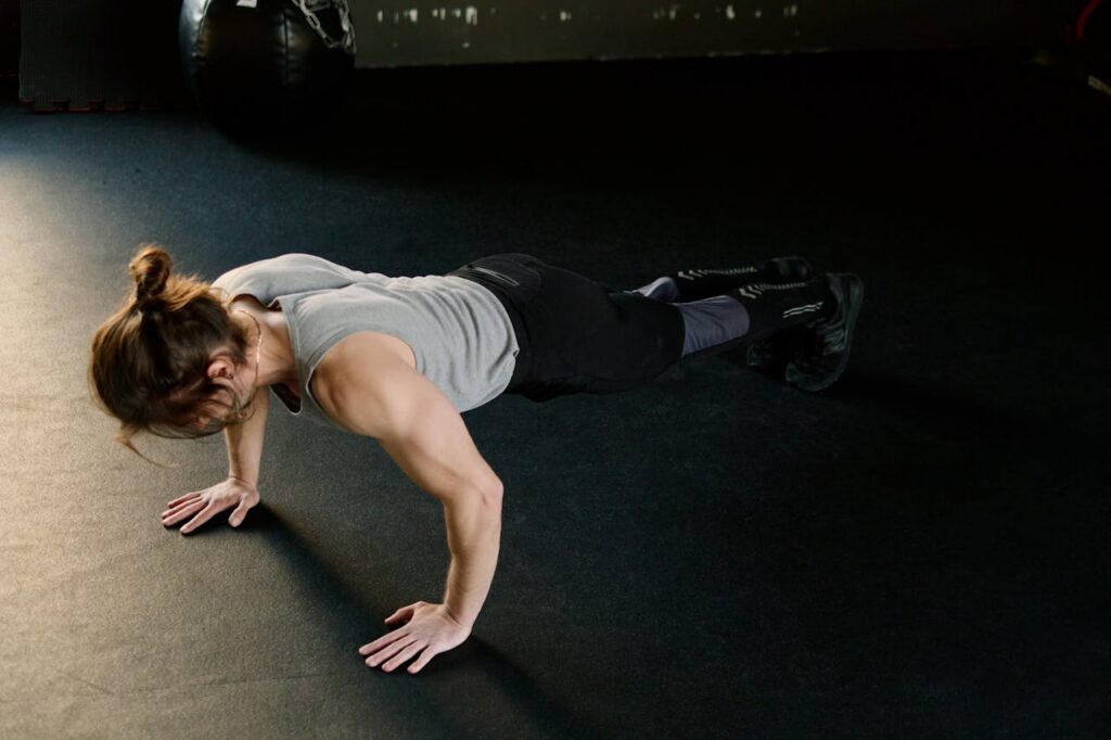 Woman performing push ups on a gym floor during a workout for weight management