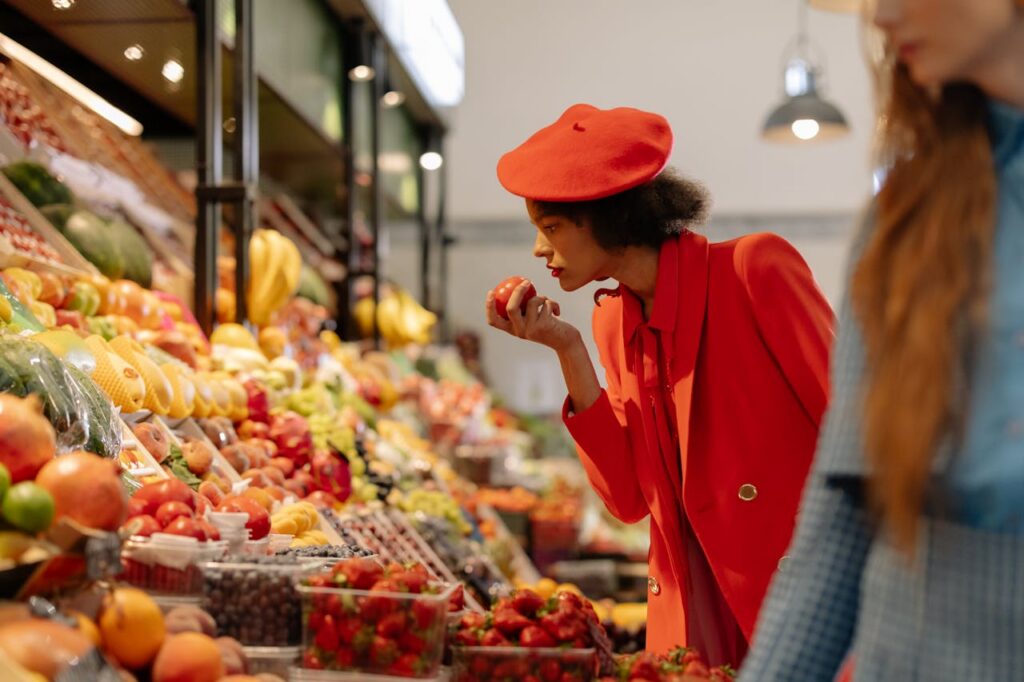 Woman smelling ripe stone fruit at a market stall to check aroma and freshness
