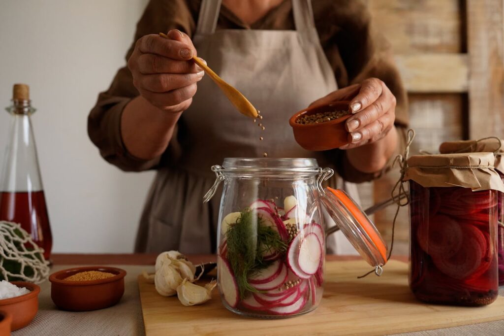fermented vegetables in glass jars with sliced radish and herbs