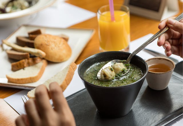 Bowl of soup with bread and juice on a tray, showing why bone broth can break a fast.