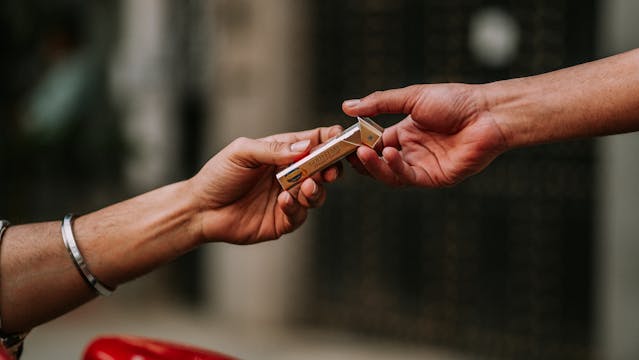 Hands passing a pack of gum. How gum use during fasting affects appetite control.